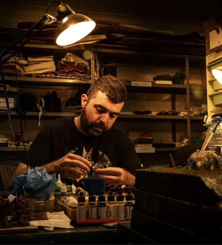 Paco pintando una miniatura en su mesa de trabajo, bajo la luz de los flexos